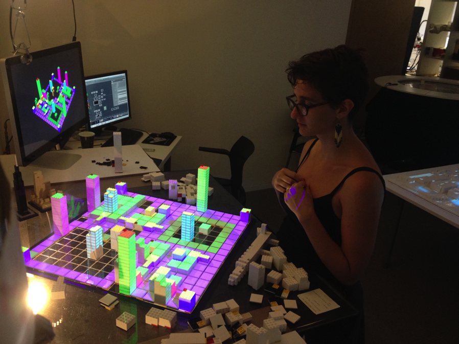 A Tactile Matrix table glowing purple and green with Lego towers, next to a screen showing the 3D model